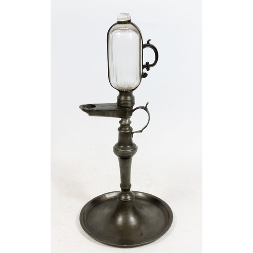 381 - Continental pewter whale oil lamp clock, 19th century, the glass reservoir enclosed within pewter ho... 