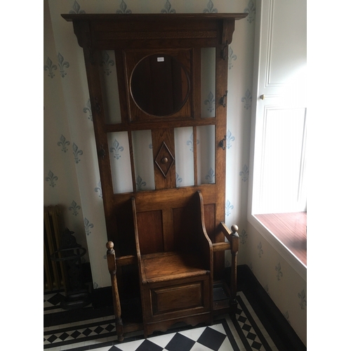 614 - 20th century oak hallstand having central circular mirror above settle style seat with hinged storag... 