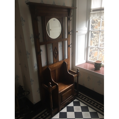 614 - 20th century oak hallstand having central circular mirror above settle style seat with hinged storag... 