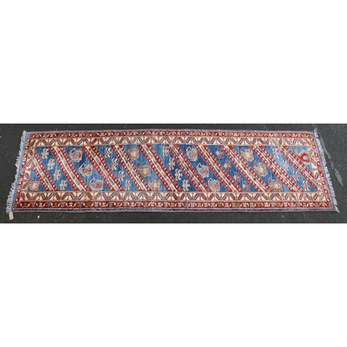 629 - Kazak style runner, polychrome geometric motifs and stripes on a blue ground within conforming borde... 