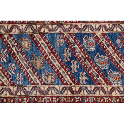 629 - Kazak style runner, polychrome geometric motifs and stripes on a blue ground within conforming borde... 