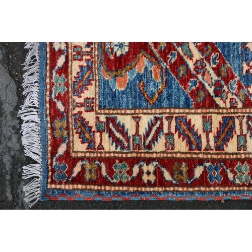 629 - Kazak style runner, polychrome geometric motifs and stripes on a blue ground within conforming borde... 