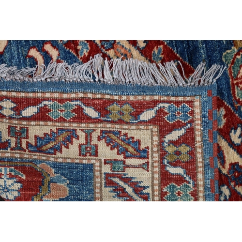 629 - Kazak style runner, polychrome geometric motifs and stripes on a blue ground within conforming borde... 