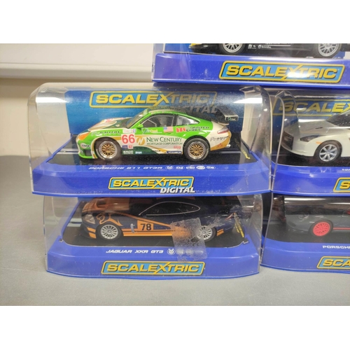 124 - Scalextric. Five 1/32 scale racing car models in perspex cases to include Porsche 997 C3079, Nissan ... 