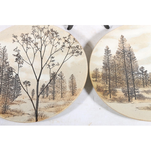 58 - Three Studio Pottery sgraffito decorated with forest scenes wall plates, 27cm diameter.