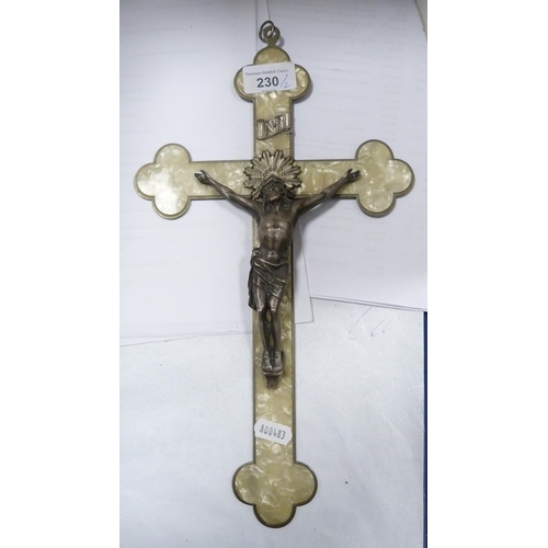 230 - Ecclesiastical-style crucifix on a white metal backing, on simulated mother of pearl ground, and an ... 