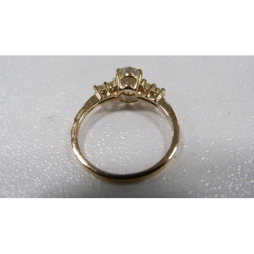 242 - Lady's dress ring set with a faux diamond flanked by small brilliants to the shoulders, 1.7g gross.