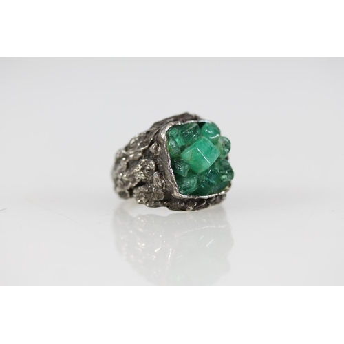 502 - Modernist silver ring with uncut green stones set within a textured band, size R.