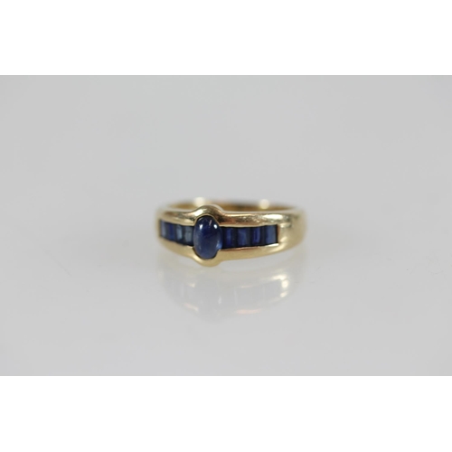 503 - Yellow metal ring set with pave sapphires flanking a central cabochon sapphire, size O/P, 3.6g, test... 