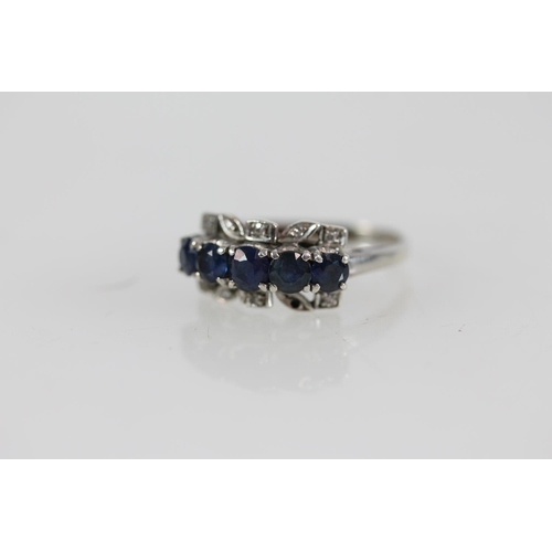 504 - White metal ring set with five round cut sapphires and small diamond chips.