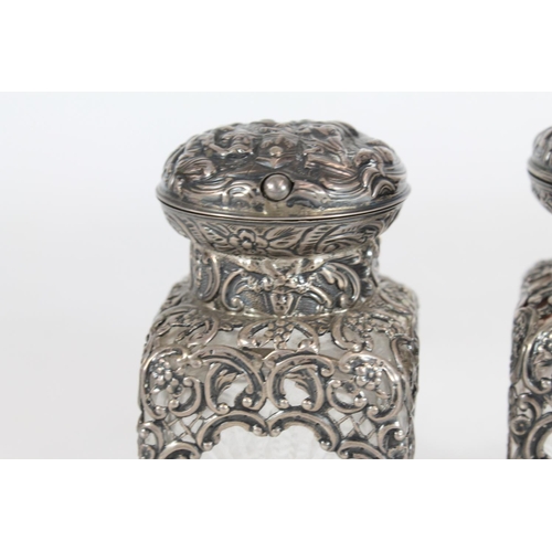 550 - Pair of Victorian cut glass toilet bottles with silver covers and mounts decorated with repoussé cla... 