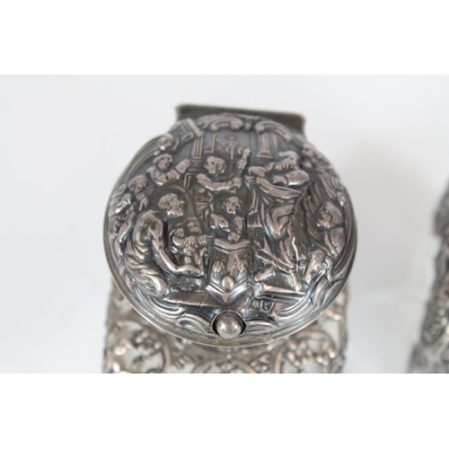 550 - Pair of Victorian cut glass toilet bottles with silver covers and mounts decorated with repoussé cla... 