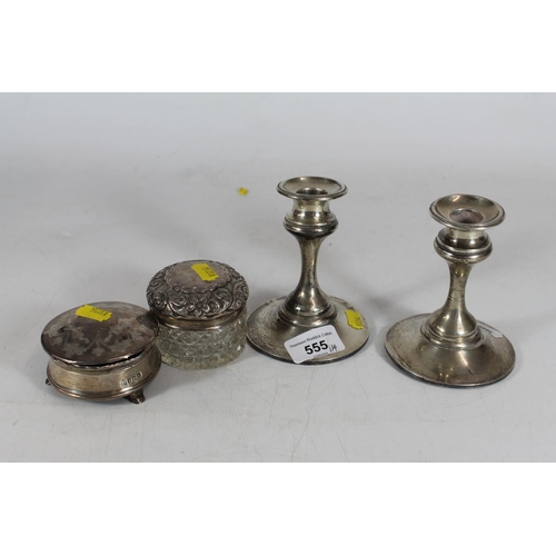 555 - Pair of hallmarked weighted silver candlesticks and two silver dressing table jars.