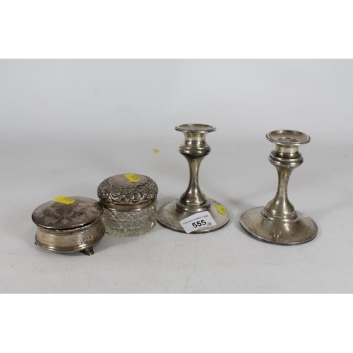 555 - Pair of hallmarked weighted silver candlesticks and two silver dressing table jars.