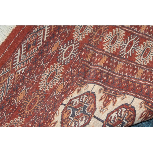 684 - Bokhara rug in rust red and cream with repasting geometric motifs, 196cm x 145cm.