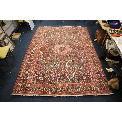 685 - Large Persian carpet in reds and polychrome decoration, 310cm x 210cm.