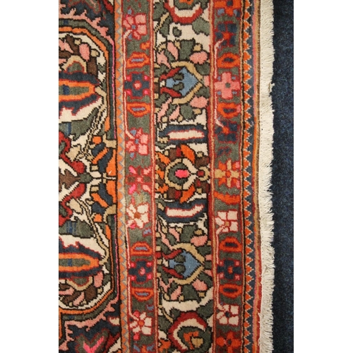 685 - Large Persian carpet in reds and polychrome decoration, 310cm x 210cm.