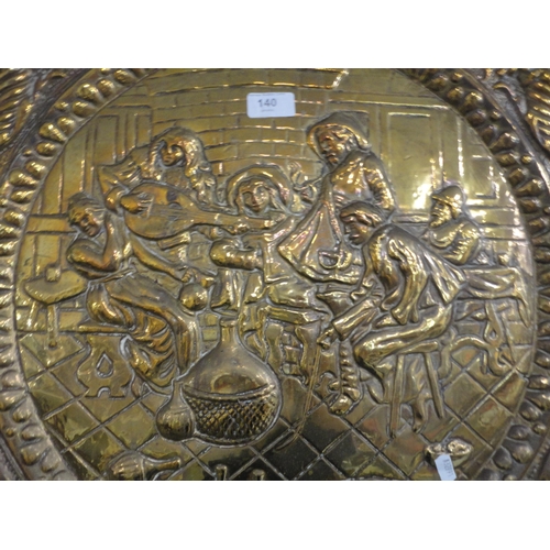 140 - Embossed brass wall charger depicting a tavern scene.