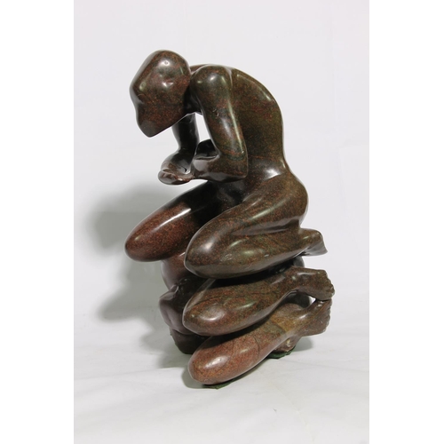 176 - Carved serpentine figure of a male seated on another body, 40cm high.