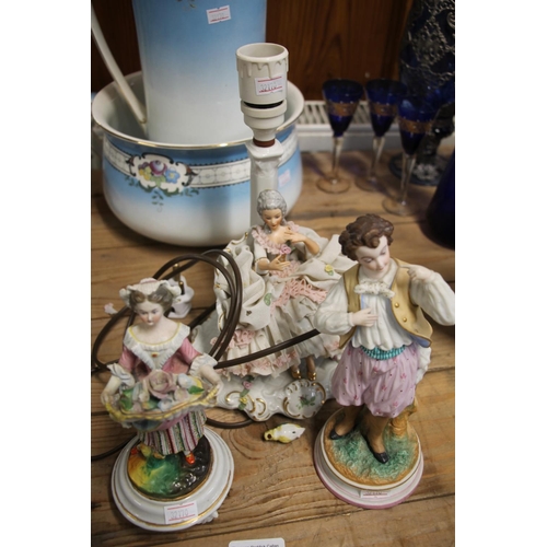 97 - Two continental porcelain figurines, largest 22cm high, and a lace figurine table lamp.