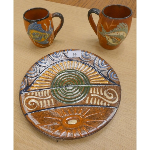99 - Two Studio Pottery fish pattern mugs and a wall plaque.