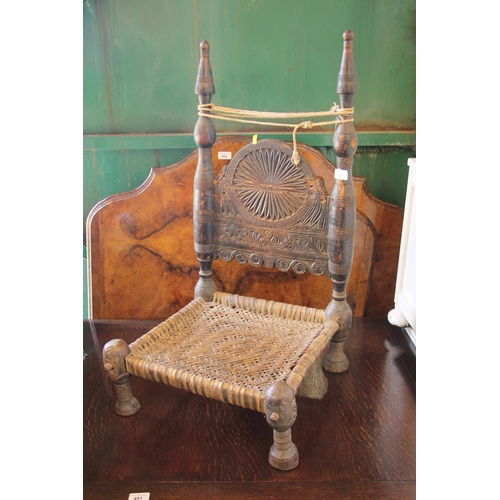 490 - Afghan nomad low chair with heavily carved back and woven seat.