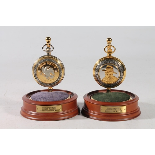 75 - Two John Wayne pocket watches, in glass domed watch holders, 14cm high.