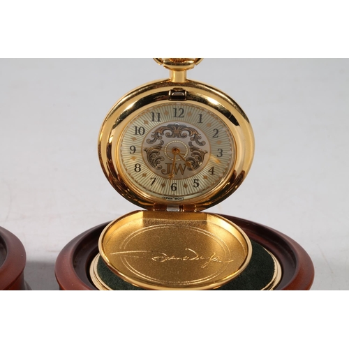 75 - Two John Wayne pocket watches, in glass domed watch holders, 14cm high.