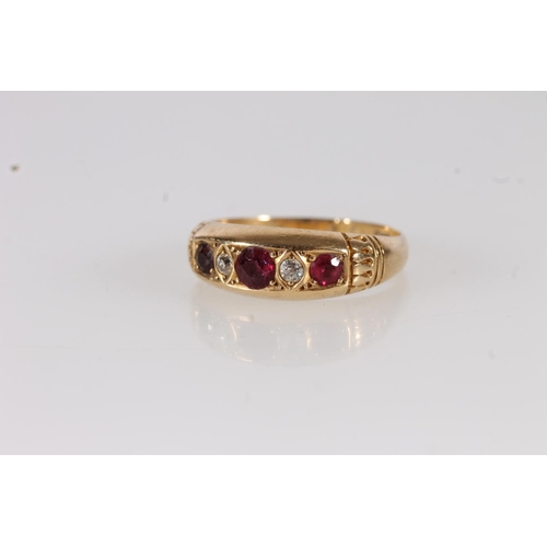 115 - Edwardian 18ct gold ruby and white stone ring, the three round cut rubies interspersed with two smal... 