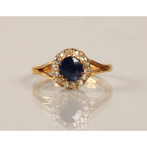 101 - 22ct gold ring set with a central blue gem surrounded by diamonds, ring size M, 5.2g