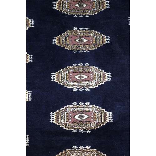 418 - Bokhara rug, the row of cream geometric guls on a blue field within geometric borders, 215cm x 130cm... 