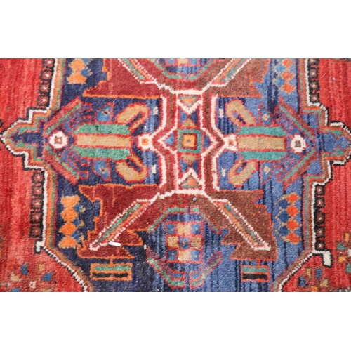 419 - Persian Shiraz region rug, the central blue geometric medallion on a red ground, bordered with black... 