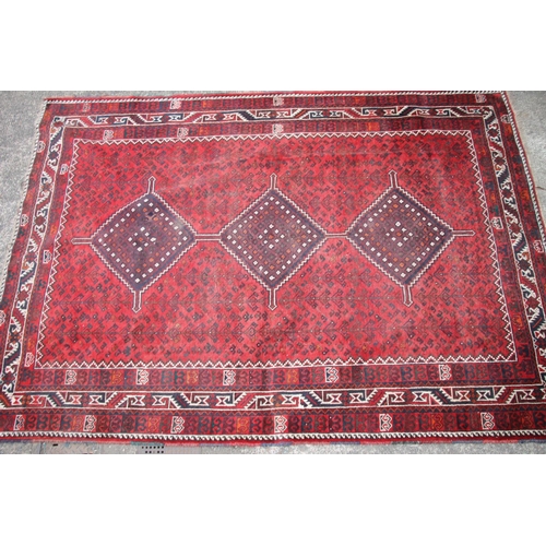 420 - Persian nomad tribal rug, the three central medallions on a red ground, 307cm x 215cm.