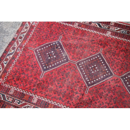 420 - Persian nomad tribal rug, the three central medallions on a red ground, 307cm x 215cm.