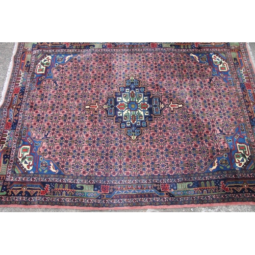 421 - Persian rug, the cream and blue central medallion on a light red ground with repeating floral patter... 