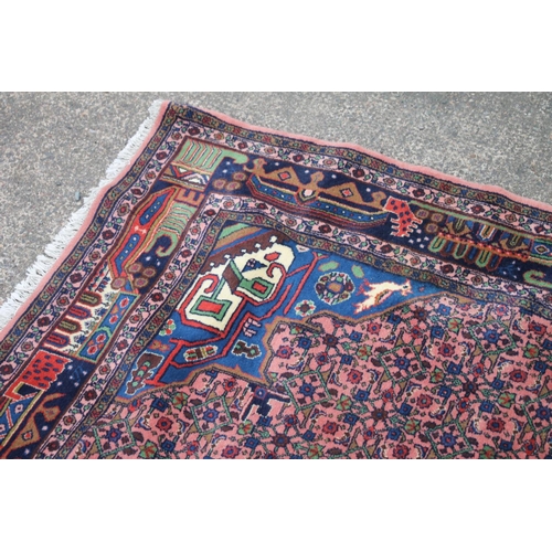 421 - Persian rug, the cream and blue central medallion on a light red ground with repeating floral patter... 