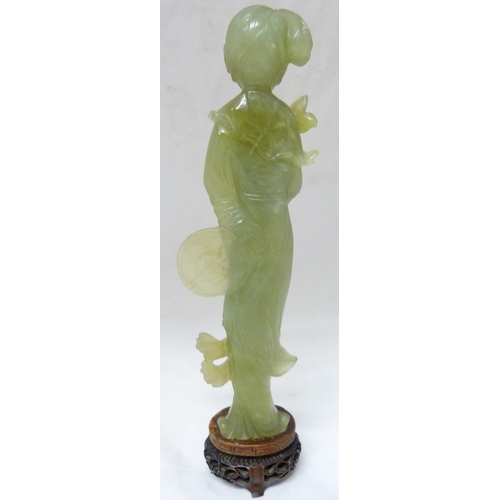 352 - Chinese carved lime jade figure of a Geisha, probably Republic period, holding a lotus flower in her... 