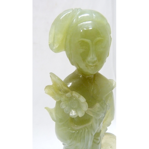 352 - Chinese carved lime jade figure of a Geisha, probably Republic period, holding a lotus flower in her... 