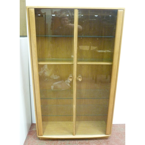 507 - Ercol beech and elm display cabinet, with twin glazed doors enclosing wooden and glass shelves, the ... 