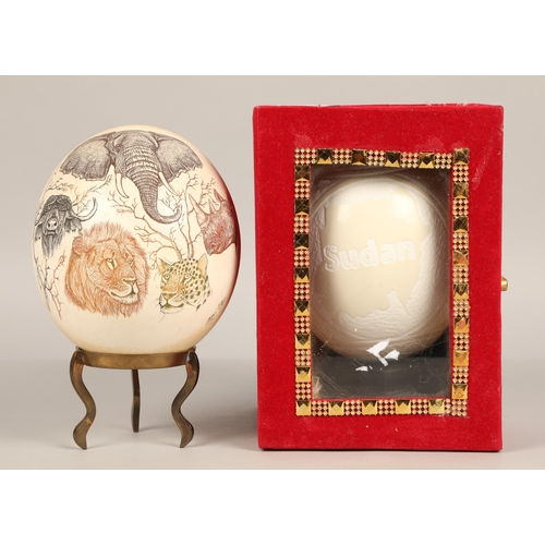 247 - Two scrimshaw ostrich eggs, one carved with Sudan design and another with Safari animals