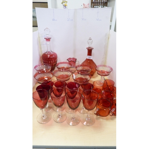 163 - Collection of cranberry glass items to include two decanters, seven dishes, jug, drinking glasses et... 