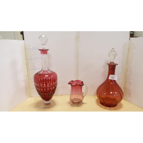 163 - Collection of cranberry glass items to include two decanters, seven dishes, jug, drinking glasses et... 