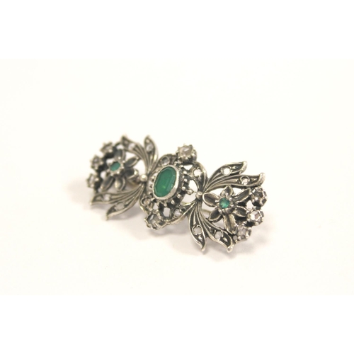 94 - Continental silver floral brooch with three collet set emeralds surrounded by old cut diamonds.