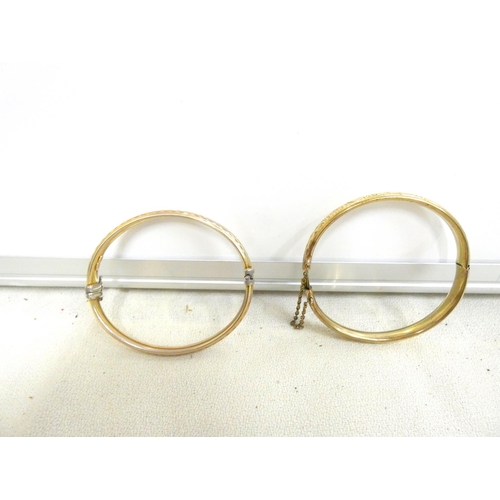 95 - Two hinged rolled gold bangles.