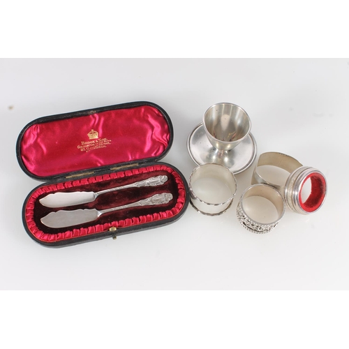 591 - Pair of hallmarked silver butter knives, silver egg cup and four silver napkin rings, silver weight ... 