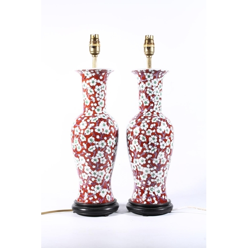 5 - Pair of Chinese pottery baluster table lamps decorated with white prunus on red ground, 49cm high.