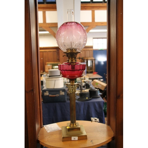 50 - Late 19th century oil lamp, with brass Corinthian column base, cranberry glass reservoir and round c... 