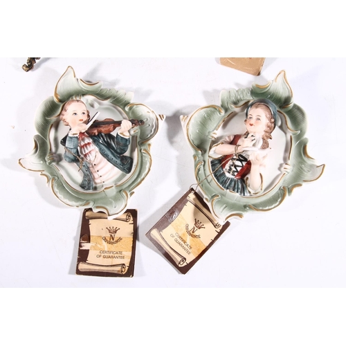 59 - Two Capodimonte figurines and two Capodimonte wall plaques.