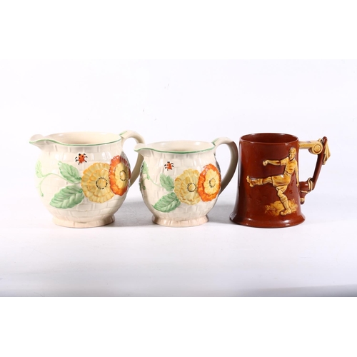 84 - Two Art Deco style jugs together with a footballing mug.