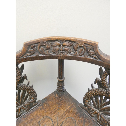 344 - Carved oak corner chair with mask to the top rail above repousse splats and central turned column, t... 